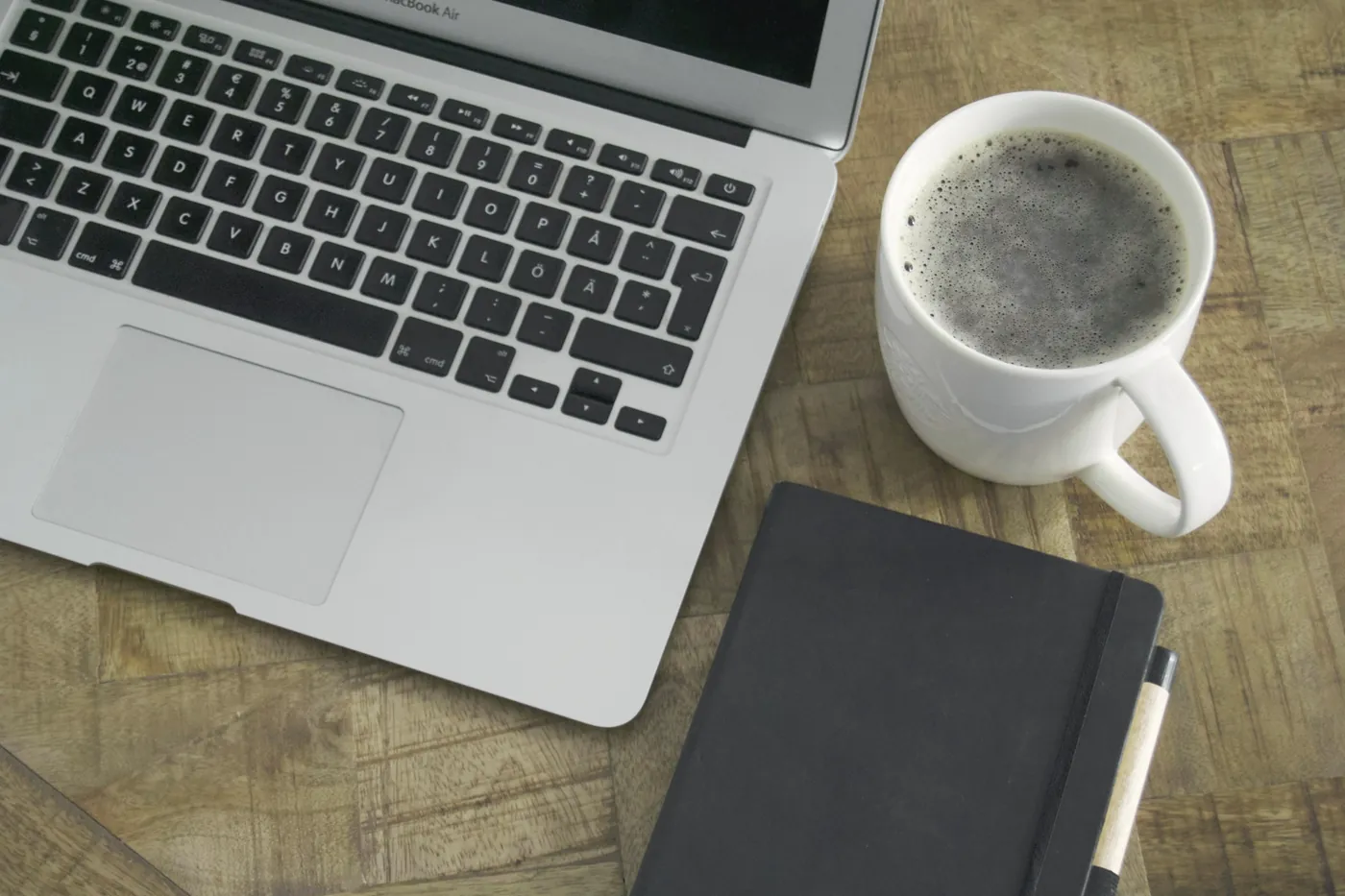 Laptop, koffie en notitieboek op een houten tafel