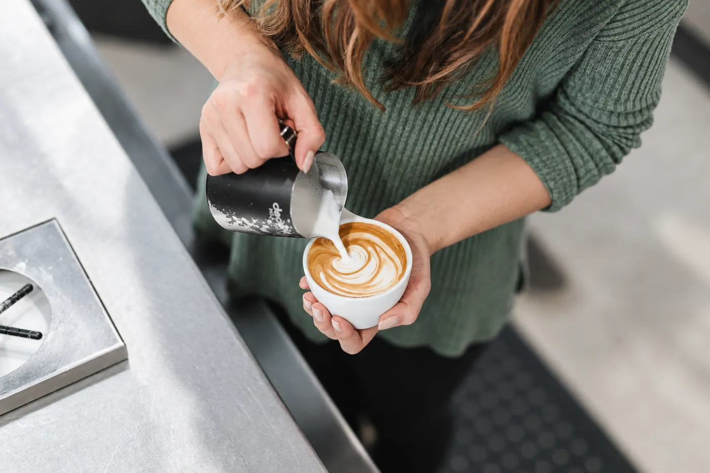 Barista schenkt melk in een kop koffie